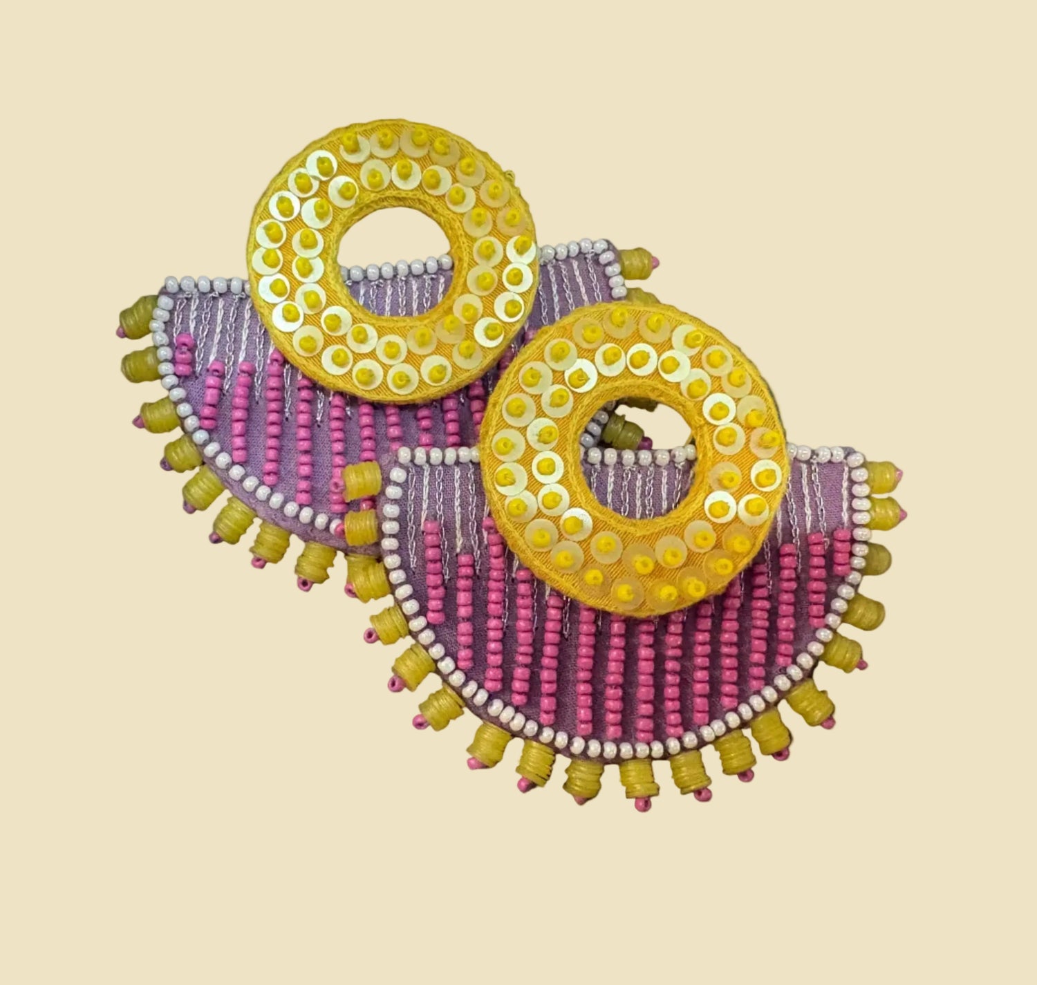 Decorative earrings with yellow and pink beads on a dark surface